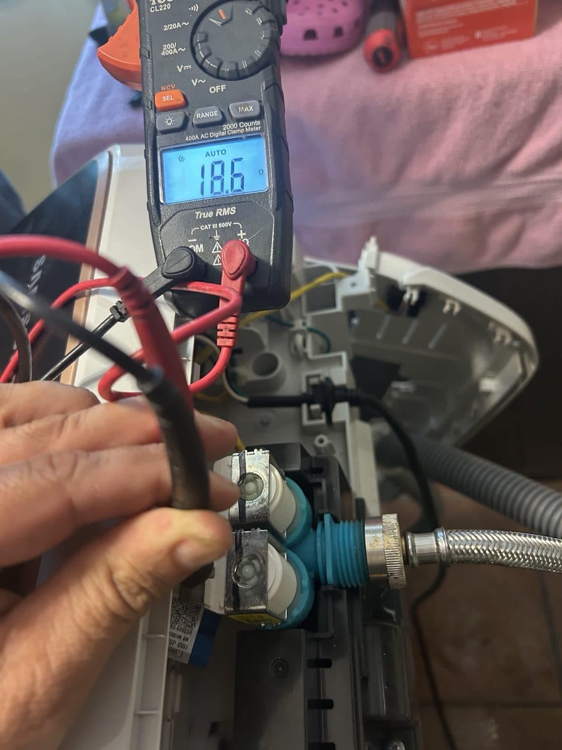 Clamp meter testing a front-load washer's water-inlet valve