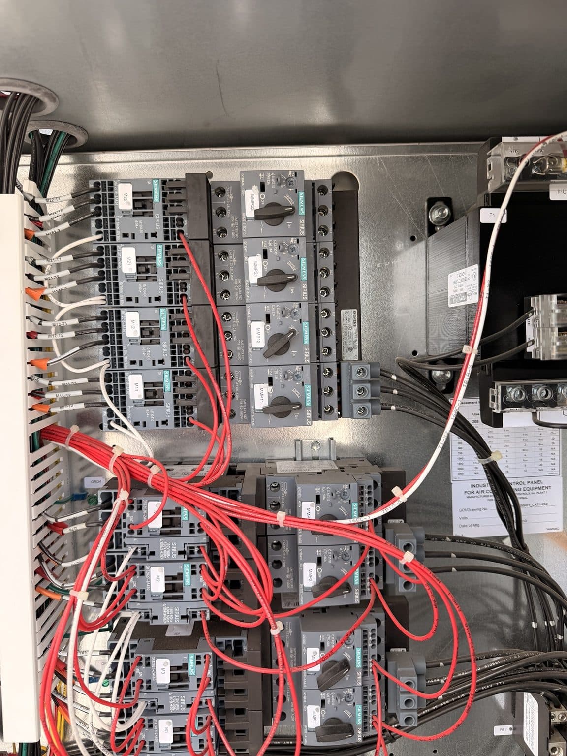 Technician's hand working inside a commercial rooftop HVAC electrical control panel