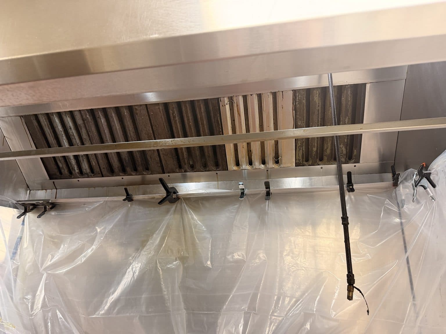 Commercial kitchen hood filters partially cleaned, showing before-and-after contrast